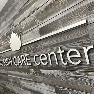 3D Letters and 3D Logo with Brushed Aluminum Metal Faces and black Returns stud-mounted to textured Lobby Wall 